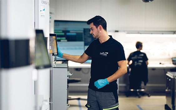 Materialise employee in a production area, viewing a screen on a 3D printer