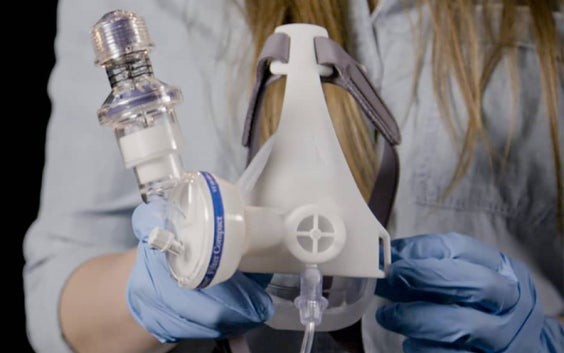 Woman holding a Materialise passive NIP mask in gloved hands